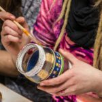 a group of people sitting around a table with a jar of paint